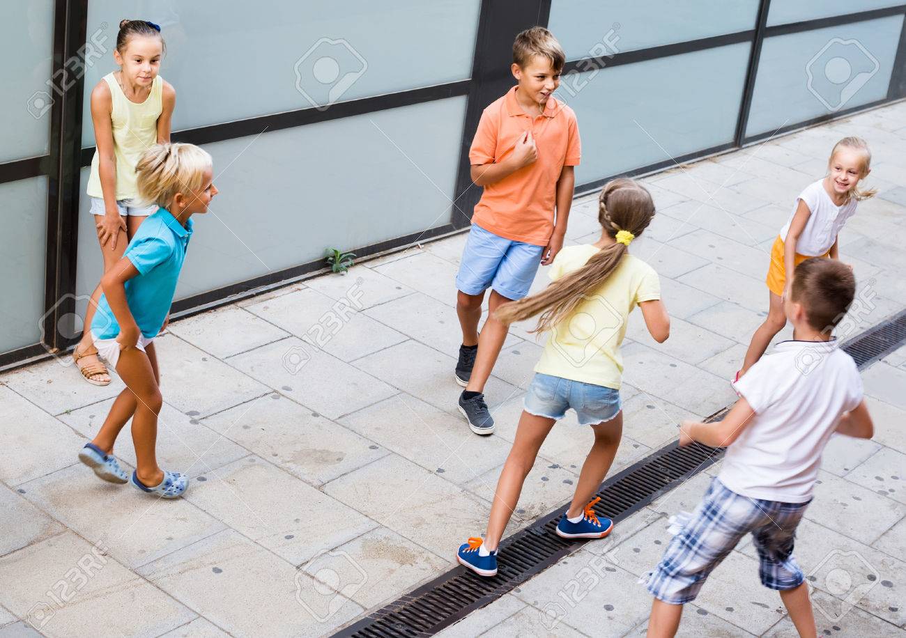 kids actively playing and running together on street on summer d